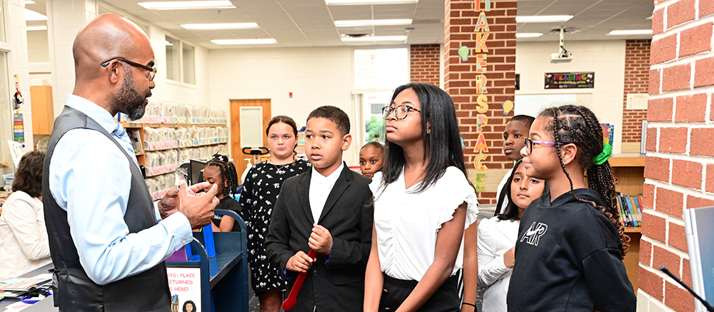 Dr. John Pace speaking with students in a media center